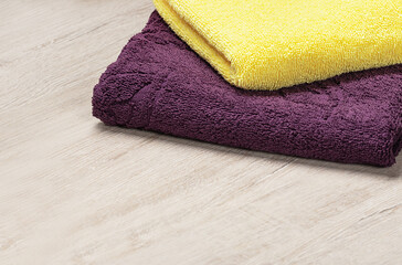 Obraz na płótnie Canvas Towels in contrasting colors on a light background. Yellow and purple bath towels 