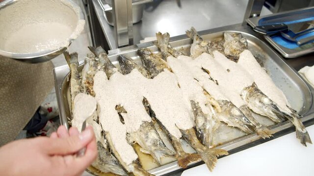 Close-up of male chef hands preparing pollock fish with sauce in kitchen