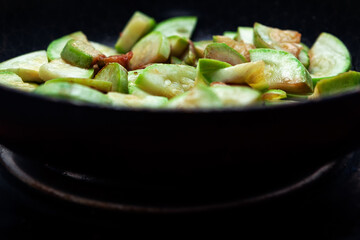 Zucchini are fried in a pan . Traditional vegetable rustic cooking