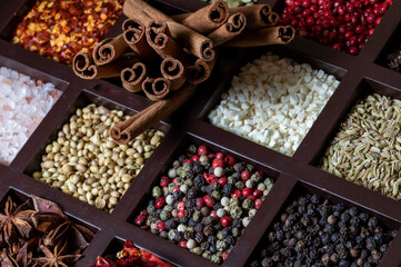 Close up of a wooden compartment box filled with various whole dry spices.