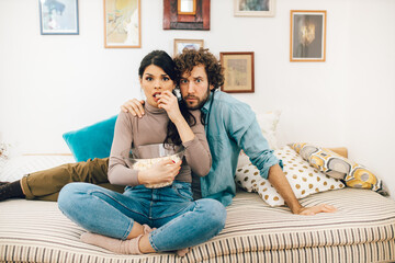 Fototapeta na wymiar Young couple watching tv and eating popcorn
