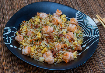 Yakimeshi is rice and eggs, shrimp, vegetables and more in the black plate. Asian food.