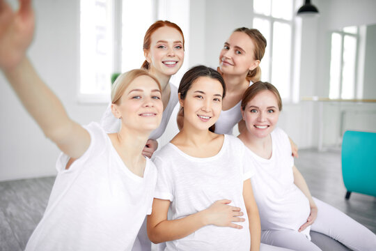 happy pregnant women gathered together in fitness ball, take photo and relax
