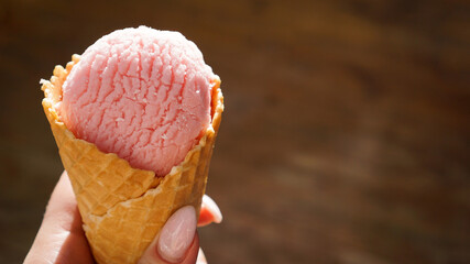 Close up image of woman hand holding raspberry ice cream