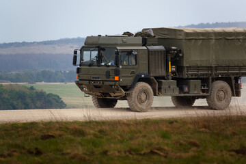 MAN SV 4x4 army logistics vehicle driving along a dusty stone track on a military battle exercise,...