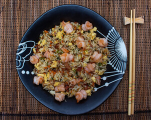 Yakimeshi is rice and eggs, shrimp, vegetables and more in the black plate. Asian food.