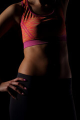 The female belly is perfectly muscled and trained and the whole set against a black background and the hands rest on the hips