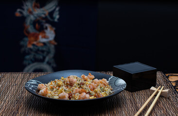 Yakimeshi is rice and eggs, shrimp, vegetables and more in the black plate. Asian food.