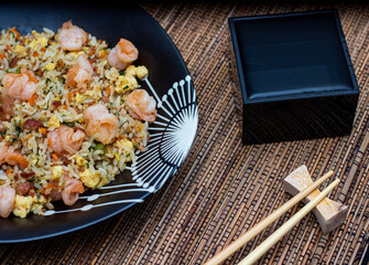 Yakimeshi is rice and eggs, shrimp, vegetables and more in the black plate. Asian food.