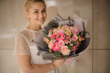 delicate bouquet of fresh roses and ranunculus in hands of happy woman