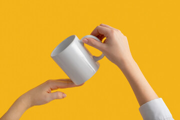 mockup ceramic white coffe cup or mug in female hands on yellow background with copy space. Blank template for your design, branding, business. Real photo. Woman in shirt casual style