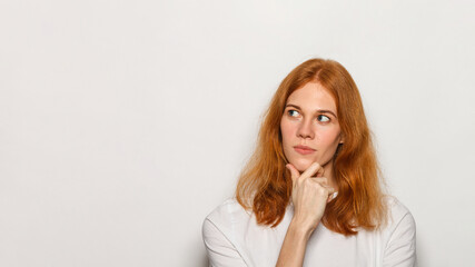 Thinking woman portrait. Red hair woman wearing white t-shirt isolated