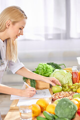 side view on Young Dietitian writing diet plan,table with different healthy products