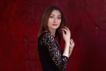 Portrait of a young woman with long brown hair, on a red textured background