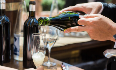 Manos de camarero sommelier sirviendo champagne en una copa