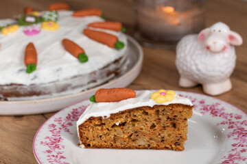 Eastern carrot cake slice with mascarpone topping and carrot marzipan, flower, eggs and rabbit decoration with a sheep figure in the background