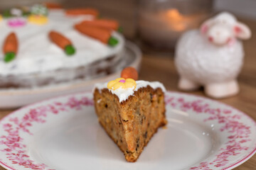 Eastern carrot cake slice with mascarpone topping and carrot marzipan, flower, eggs and rabbit decoration with a sheep figure in the background