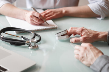 Doctor measures patient's oxygen saturation and pulse using pulse oximeter in a clinic.