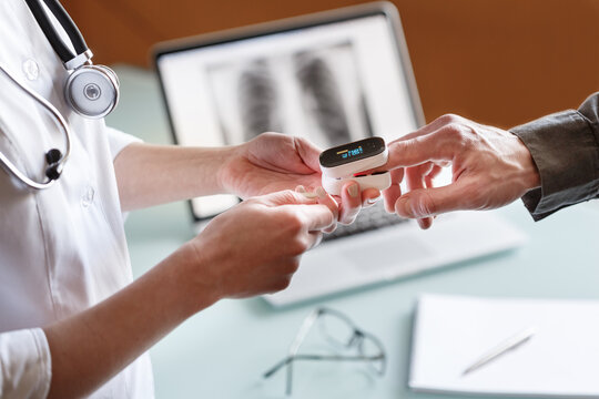 Doctor measures patient's oxygen saturation and pulse using pulse oximeter in a clinic.