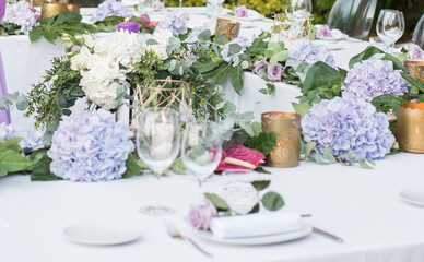 Mesa preparada y decorada para banquete de boda con mantel, servilletas, cubertería y arreglos florales