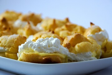Delicious princess donuts with yellow vanilla cream and whipped cream on a tray on a white background