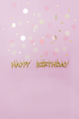 Words happy birthday made by golden candles on a pastel background decorated with confetti . Verical banner, copy space. Greeting postcard.