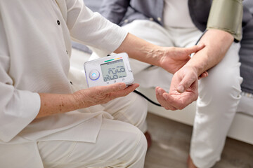 Blood pressure. Gray-haired elderly woman helping her sick husband to check blood pressure