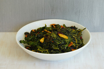 Bowl of cooked green kale salad with dried cranberries and almonds