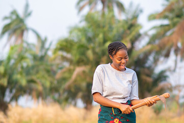 happy female african farmer working with a hoe on her farm