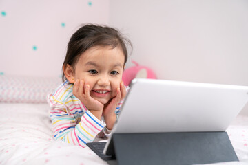 Happy toddler watching content in her digital tablet.