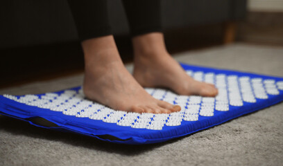 Woman is using acupuncture applicator mat for her legs.