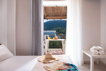 Closeup of open door to summer view balcony with terrace furniture, wooden roof ceiling, white interior of empty bedroom in European country side apartment