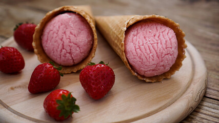 Strawberry ice cream in a waffle cone. Red berries and ice cream balls