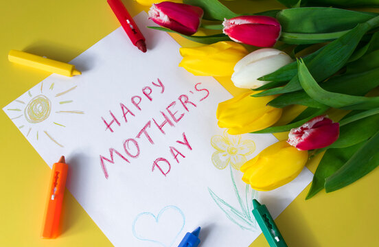 "Happy mother's day" greeting card for Mom drawn by kid on Mother's Day with colorful tulips in bouquet of flowers and crayon markers on yellow background. Congratulations and surprise for Mom.