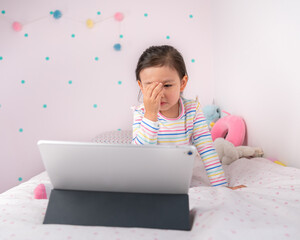 Toddler girl covering her face while finding something forbidden on the internet