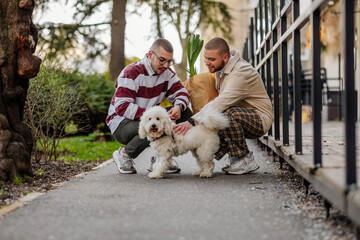 Gay male couple cuddling adorable dog in front of store where they were in shopping