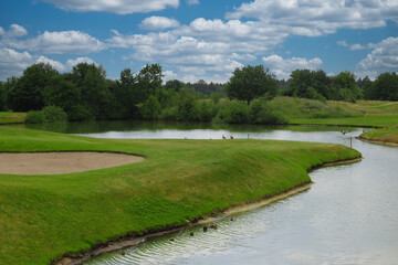 Fototapeta na wymiar Beautiful golf course landscape with sand trap, water hazard and dense vegetation
