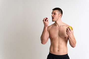 Fototapeta premium Man holds apples in fitness white background isolated healthy man fitness, sexy food lifestyle background, bodybuilding nude. Hand energy red, wellness chest