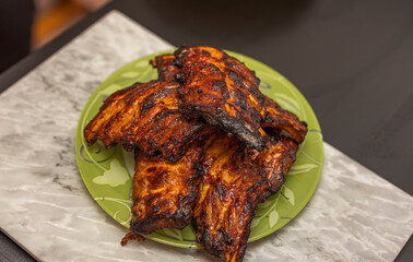 Close up view of grilled pork ribs on green plate.