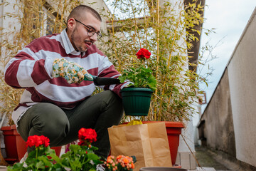 Male gardener planting flowers on balcony