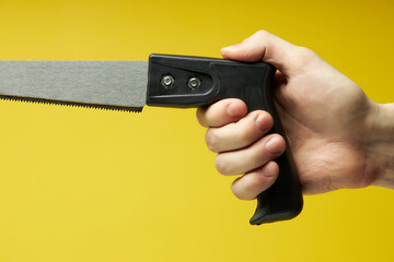 close-up Crosscut saw with black handle isolated on yellow background