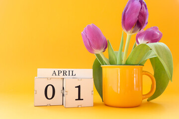 Calendar for April 1: cubes with the numbers 0 and 1, the name of the month April in English, a bouquet of tulips in a tea mug