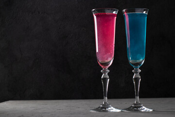 Shimmer edible glitter sparkling pink and blue wine in two tall glasses on dark gray background. Copy space