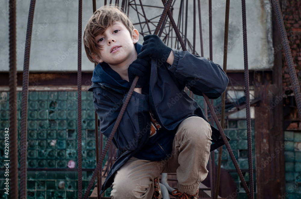 Wall mural Fashionable boy ruffer climbs metal structures at heights in an abandoned factory. Dangerous entertainment for children. Parkour. Extreme sports. Danger of walking. Suicide. Troubled teenager. Tomboy