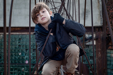 Fashionable boy ruffer climbs metal structures at heights in an abandoned factory. Dangerous...