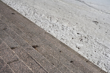 Granite steps on the embankment of the ice-covered river.