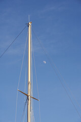 Obraz premium The yacht's mast against the blue sky with the moon.