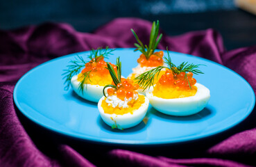 eggs stuffed with red caviar tasty and healthy serving as in a restaurant on a blue plate the best...