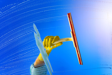 Window cleaner using a squeegee or wiper to wash a window glass. Hand in yellow glove hold cleaning...