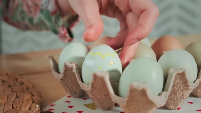 The girl puts the painted Easter egg in the basket. Close-up.